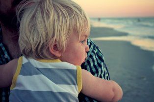 Mother holding her young son while walking on the beach