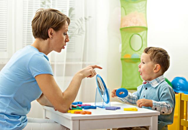 Teacher speech therapist with young child learning speech development